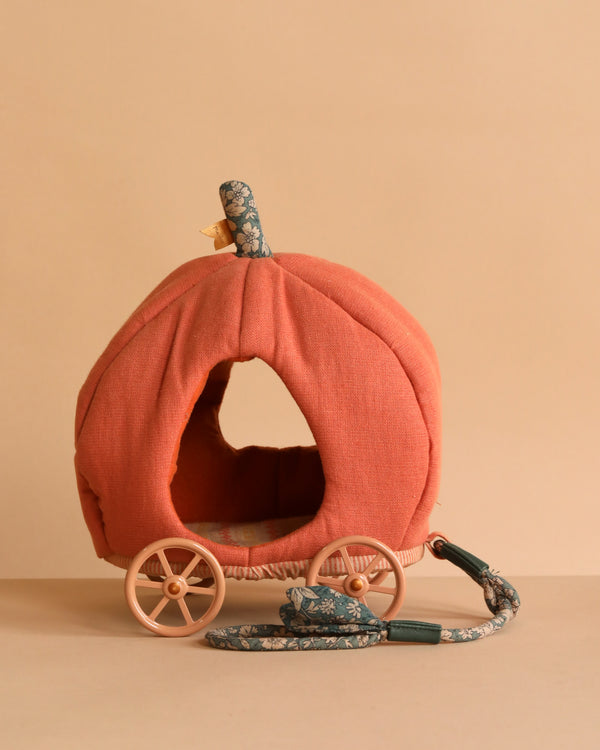 The Maileg Pumpkin Carriage, Mouse is a soft fabric fairytale toy with wooden wheels, a floral pull string, a front opening, and top stem—ideal for a royal mouse family. Displayed against a beige background.