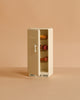 A small beige refrigerator, door ajar to show mini food on two shelves, sits against a plain background—an ideal addition to your Maileg Kitchen Set with Chef Mouse or mouse playset.