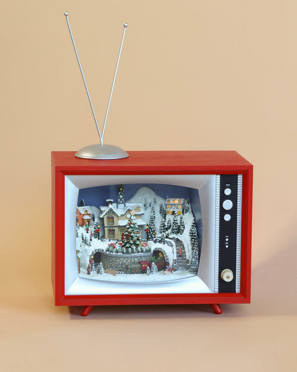 A whimsical Christmas music box diorama inside a Christmas Music TV With Depot And Train, featuring a snowy village scene with small houses and festive decorations.