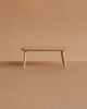 The Maileg Coffee Table, Mouse - Nature is a small, minimalist wooden bench with three legs, perfect for adding charm to any Mouse hole Farmhouse décor. Set against a light brown background, it’s reminiscent of a mouse-size coffee table.