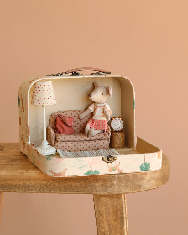 The Maileg Little House Living Room Travel Set includes a small suitcase diorama with a cozy mouse-sized living room—complete with a toy mouse, vintage floor lamp, pillow, clock, and charming patterned details.