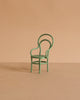 A Maileg Vintage Chair, Mouse Size - Mint, with a rounded back and curved armrests sits on a plain beige surface against a matching beige background.