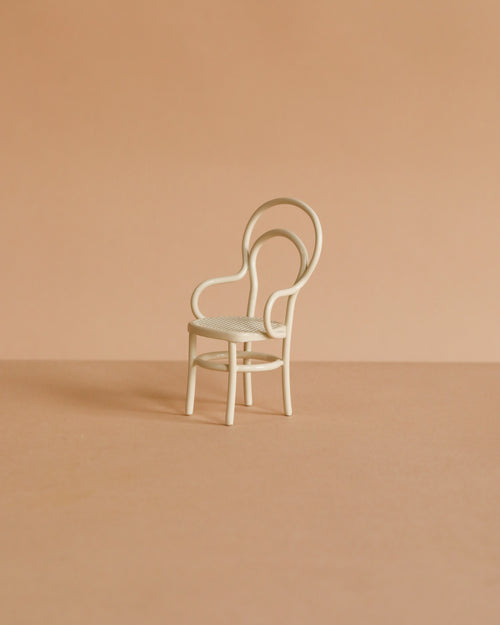 The Maileg Vintage Chair, Mouse Size - Off White is a small, white metal chair with a rounded backrest, ideal for mouse-sized furniture collections. Shown on a light brown surface with a beige background.