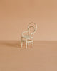 The Maileg Vintage Chair, Mouse Size - Off White is a small, white metal chair with a rounded backrest, ideal for mouse-sized furniture collections. Shown on a light brown surface with a beige background.
