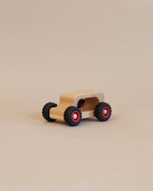 A handcrafted Fagus Wooden Oldie Car with black tires and red wheel centers, set against a plain beige background.