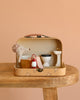 The Maileg Little House Bathroom Set, displayed in a small suitcase on a wooden table, includes miniature mouse furniture—a toilet, sink, brown tub, red lantern, and a mouse plush toy in a shower cap against a light peach background.