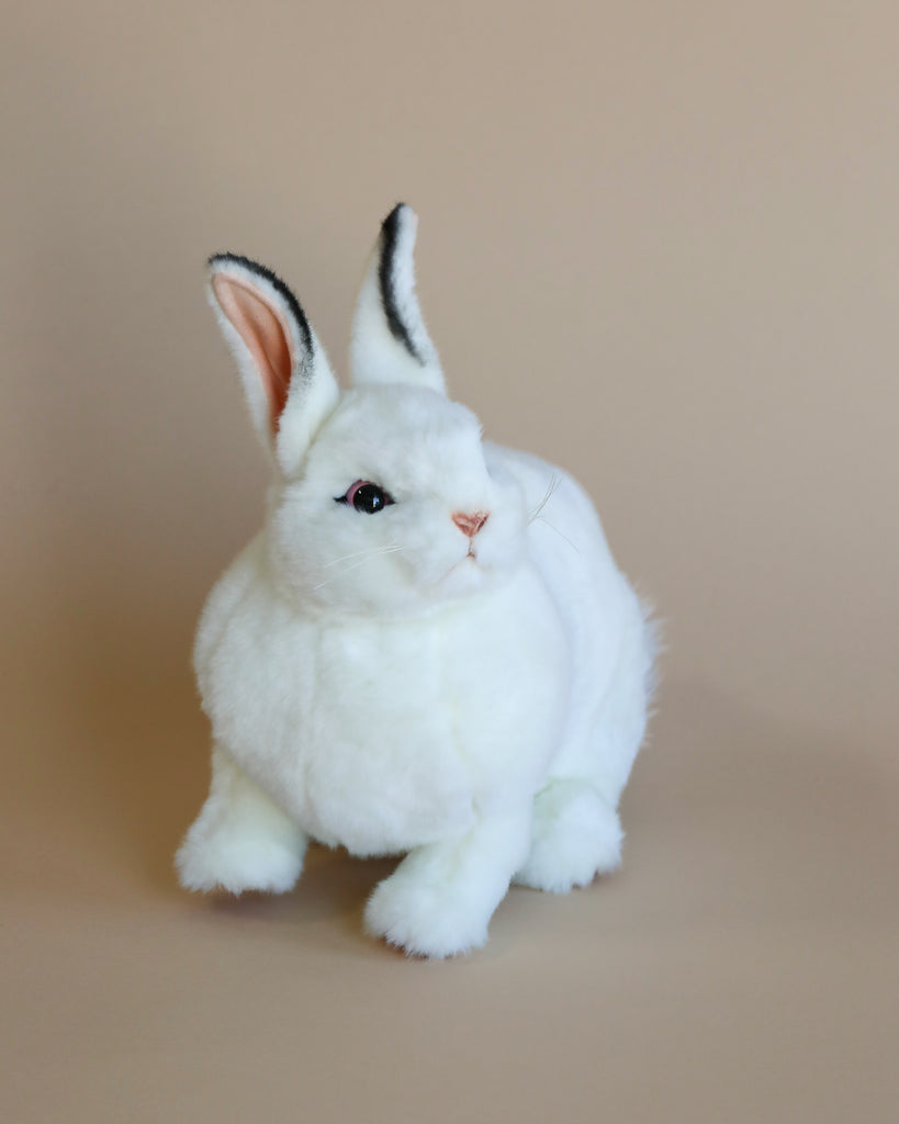 A White Bunny Stuffed Animal with upright ears and alert eyes, set against a soft beige background, hand sewn to ensure meticulous detail.
