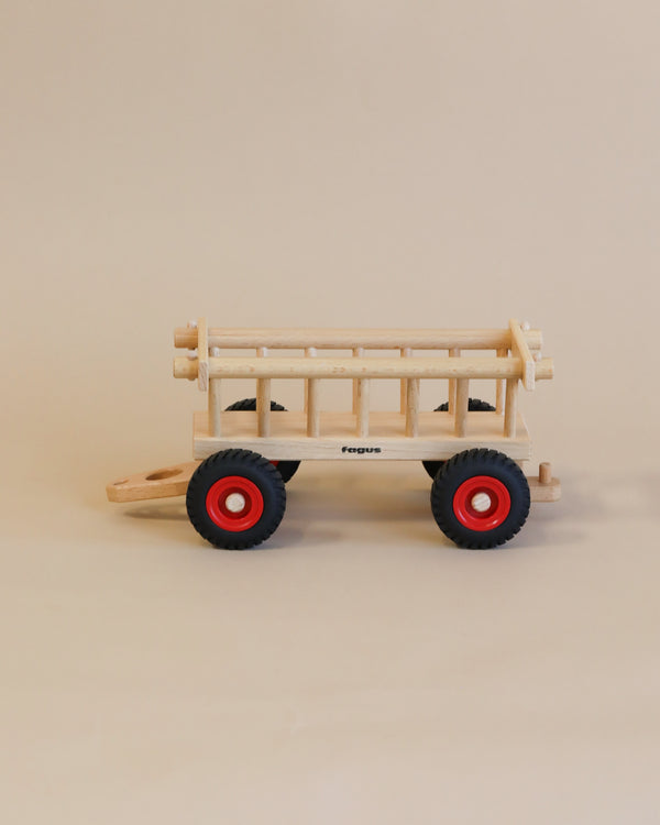 A handcrafted Fagus Wooden Hay Wagon with red wheels and a natural finish displayed against a plain beige background. The word "fagus" is visible on its side.