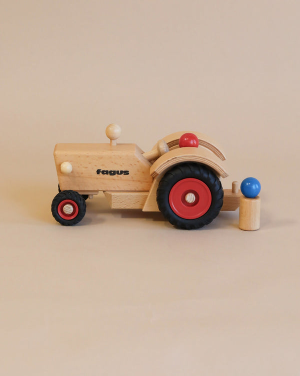 Sentence with Product Name: A Fagus Wooden Tractor with the word "fagus" printed on it, featuring a movable steering knob and colored wheels, displayed against a neutral background.