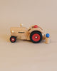 The Maileg x Fagus Tractor Set, featuring handcrafted quality and black and red wheels with the "fagus" logo, stands on a beige background beside a small wooden figure.