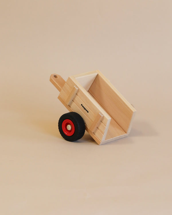 A small handcrafted Fagus Wooden Farm Cart with black and red wheels against a plain beige background.
