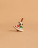 The Wooden Spinning Top - Sheep, crafted from sustainably sourced wood, features colorful rings and a sheep face design on a plain beige background.