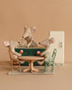 Three Maileg mice enjoy their miniature kitchen with the Maileg Kitchen Set: little sister mouse sits at the round table with mugs, another stands behind the counter, while a green cabinet and a white fridge complete the cozy scene.