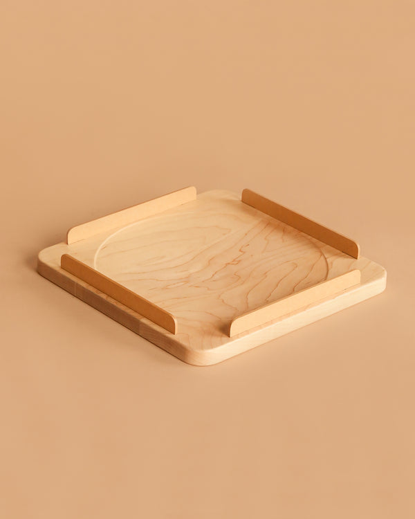 The Wooden Spinning Top Tray features a square maple wood design with rounded corners, two opposing wooden rails, and a beige surface—perfect for spinning tops.