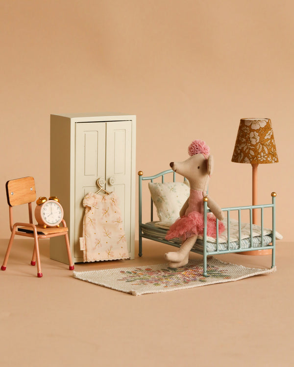 The Maileg Little Sister Bedroom Set features a Ballerina Mouse in a pink dress on a mini bed, with a wardrobe, alarm clock on the chair, vintage lamp, and rug arranged in a cozy dollhouse bedroom.