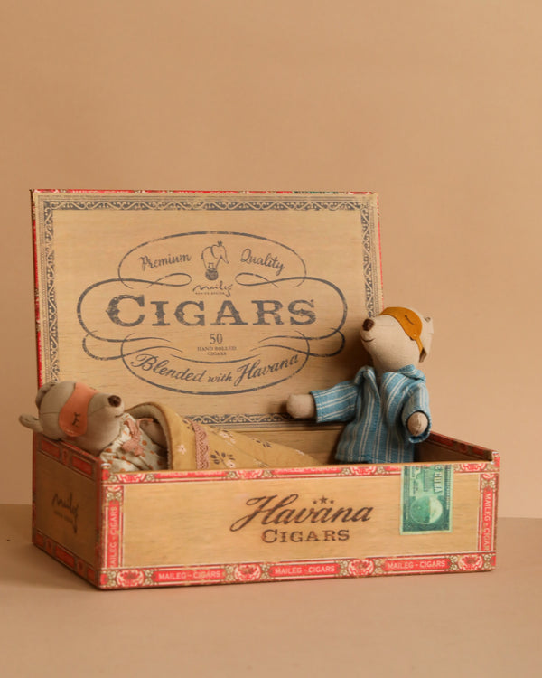 The Maileg Mum & Dad Mice in Cigar Box features two mice resting inside a vintage-style "Havana Cigars" box—one cozily tucked under a blanket, the other sitting up against a beige backdrop.