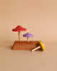 Three Wooden Mushroom Spinning Tops crafted from responsibly-sourced wood and painted in red, purple, and yellow, displayed against a neutral background, with one mushroom tipped over.