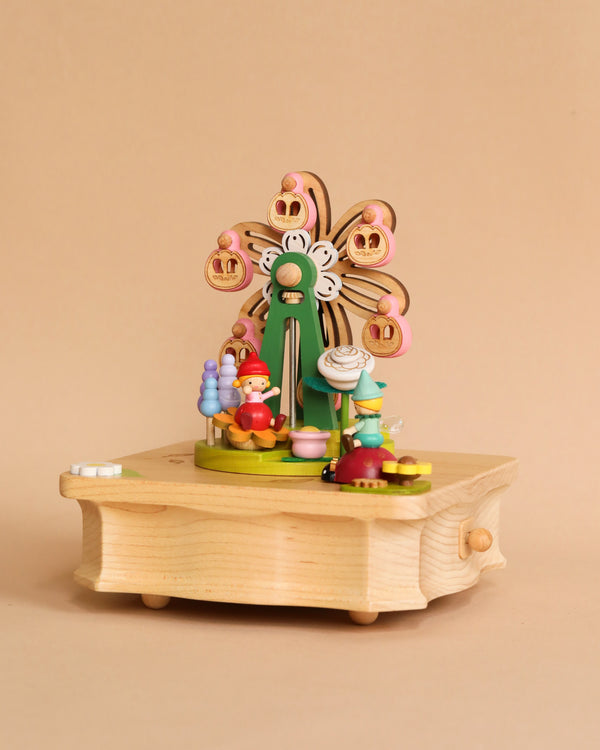 A whimsical hand cranked Ferris Wheel Fairy Music Box featuring a colorful ferris wheel design with small figures and ice cream cones, set against a pale orange backdrop.