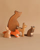The Ostheimer Handmade Wooden Woodland Animals Set features five non-toxic, handcrafted figures—a bear, fox, raccoon, deer, and rabbit—displayed on a plain beige background for a charming nature-inspired addition to any playroom.