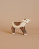 An Ostheimer Reindeer Calf figurine, handcrafted from wood, stands against a plain beige background. This piece inspired by Ostheimer toys features painted details in light brown, dark brown, and white hues with small blue eyes—perfect for imaginative play.