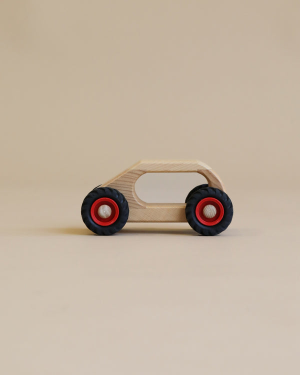 A simple handcrafted Fagus Wooden Van with a natural finish and bright red wheels, standing on a plain beige background.