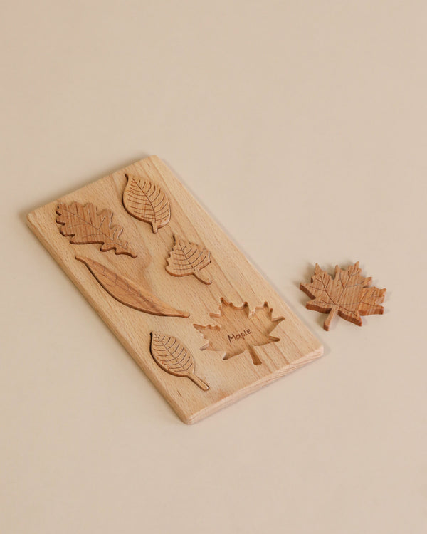 A Wooden Leaf Puzzle featuring solid wood leaf-shaped pieces neatly arranged in their corresponding slots on a beige background.