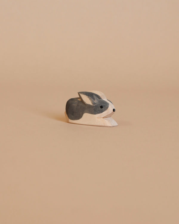 A small Ostheimer Black & White Rabbit figurine sits against a light beige background. Handcrafted with care, the wooden toy is painted in shades of gray and white, with minimalistic details giving it a simple and charming appearance—perfect for imaginative play.