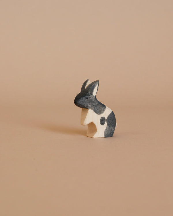 A small, handcrafted Ostheimer Black & White Rabbit figurine stands against a plain beige background. The bunny has a simple, minimalistic design with no detailed facial features, perfect for imaginative play.