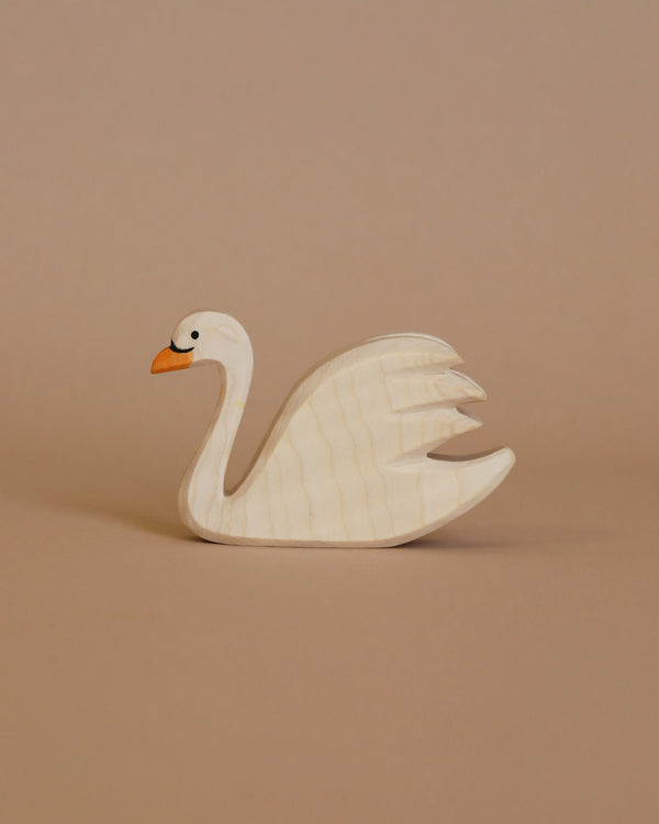 The Ostheimer Swan is a charming small wooden figurine featuring a white body, an orange beak, and intricate wing carvings. Ideal for imaginative play, this handcrafted wooden toy is showcased against a plain beige background.