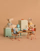 The Maileg Kitchen Set with Family features four collectible mice, dressed in colorful outfits, in a miniature kitchen scene with table, chairs, stove, and fridge—perfect for simulating family meals.