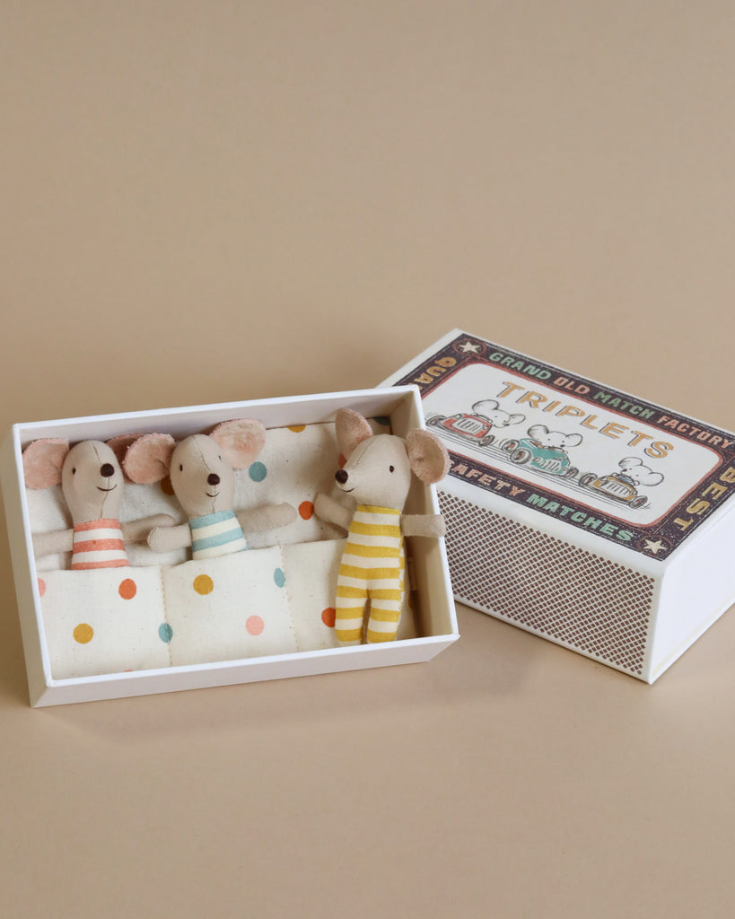 A Maileg | Triplets Baby Mice In Matchbox—likely baby mice, based on their features—dressed in cute striped and solid colored outfits, sitting inside a box labeled "grand old mice nursery rhymes.