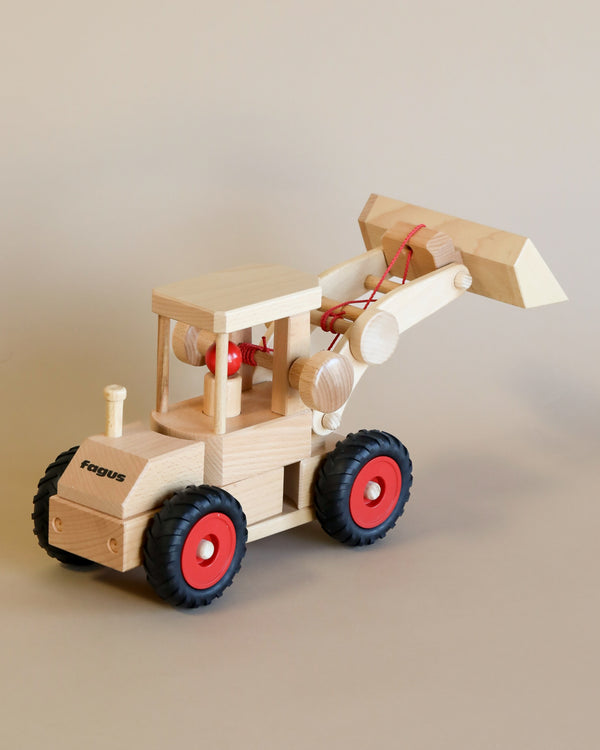 A Fagus wooden front loader with red accents and a propeller, sitting against a neutral beige background.