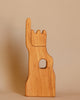 The Ostheimer Lookout - Small is a wooden sculpture shaped like a hand with the index finger raised and the other fingers folded down. This imaginative play piece also features a circular hole in the palm area and is set against a plain beige background.