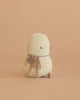The Maileg Chicken Plush, Mini is a small yellow chick stuffed toy wearing a brown ribbon and round tag, shown sitting away on a peach background.