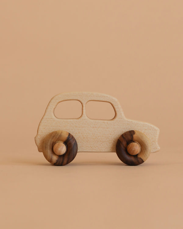The Little Wooden French Car is an eco-friendly baby toy made from natural wood, featuring a smooth finish and rounded dark wooden wheels. Shown on a light brown surface with a beige background.