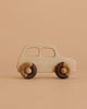 The Little Wooden French Car is an eco-friendly baby toy made from natural wood, featuring a smooth finish and rounded dark wooden wheels. Shown on a light brown surface with a beige background.