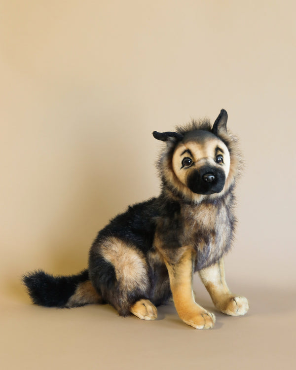 A realistic German Shepherd Puppy Stuffed Animal positioned against a plain beige background, featuring expressive eyes and detailed fur in black and tan colors.