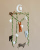 A Handmade Mobile - In The Jungle - Final Sale featuring felt animals such as a sloth, leopard, koala, and others, hanging amid green vines and white stars from a circular top with a crescent moon.