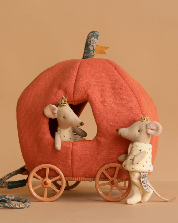 The Maileg Royal Pumpkin Carriage Set features two crown-wearing mice posed with a plush pumpkin carriage—one mouse inside, one outside—all set against a simple light brown background.