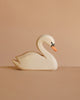 The Ostheimer Handmade Wooden Swan Family Set, featuring white bodies with orange beaks and black detailing, is displayed on a neutral brown surface against a matching solid brown background.