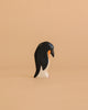 The Handmade Holzwald Penguin, Head Down features black, white, and orange colors and stands upright against a beige background—perfect for anyone seeking a sustainable toy for their collection.