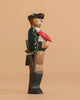 The Handmade Holzwald Pirate and Parrot features a pirate in a black hat and coat with a red parrot on his shoulder, holding a sword against a beige background—a perfect sustainable toy for any collection.