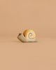 The Handmade Holzwald Snail is a small, minimalist wooden figurine with a light brown shell and simple spiral design, reflecting sustainable charm. It’s displayed elegantly on a plain beige background.