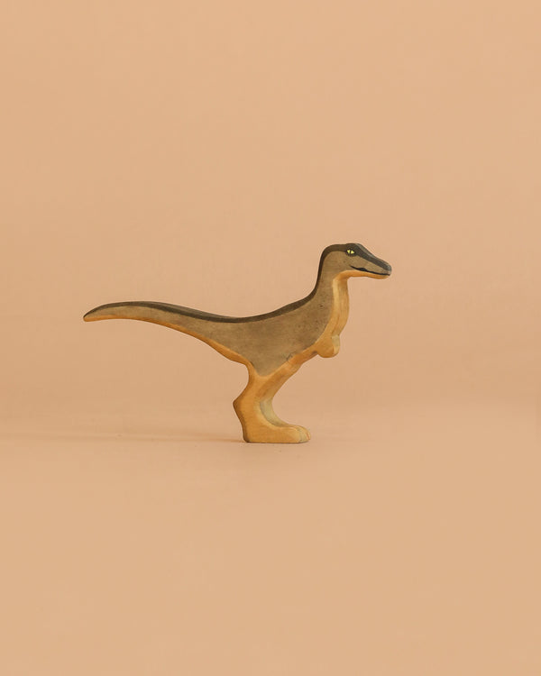 The Handmade Holzwald Velociraptor, a small wooden figurine with short arms and a long tail, stands upright against a light brown background—ideal for fans of sustainable toys.