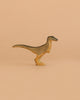 The Handmade Holzwald Velociraptor, a small wooden figurine with short arms and a long tail, stands upright against a light brown background—ideal for fans of sustainable toys.