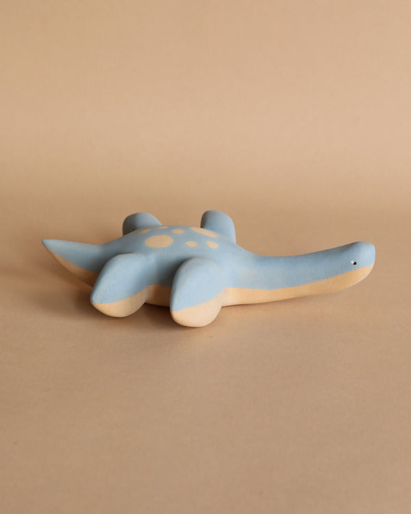 A handmade wooden Plesiosaurus dinosaur toy, featuring a smooth finish and decorative spots, set against a plain beige background. This handcrafted toy is painted with non-toxic paint.