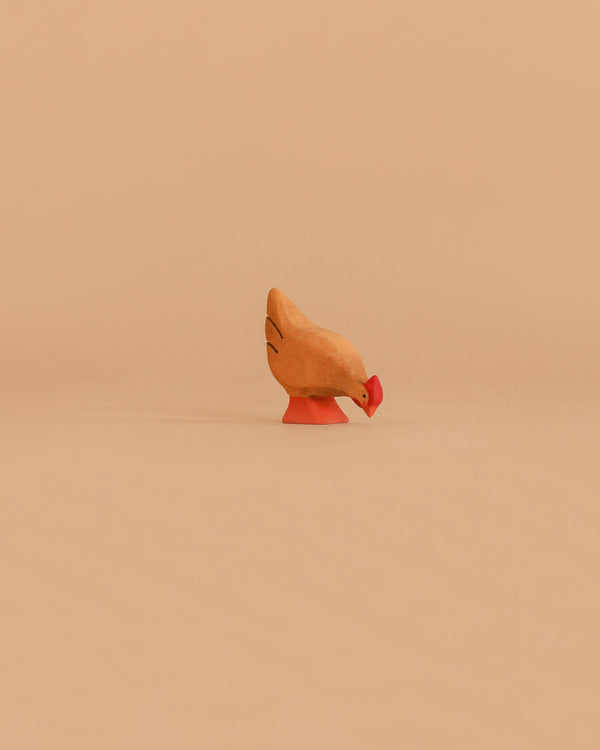 The Bumbu Handmade Wooden Brown Hen, crafted from sustainable Romanian wood and hand-painted in brown shades, is displayed on a smooth, light orange background.