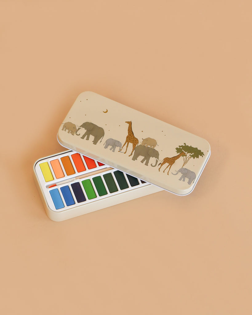 The Konges Sloejd Water Colors Paint Set - Safari is a rectangular tin box with a beige lid showing elephants, giraffes, and a tree. Inside are two rows of vibrant rectangular paint pans.