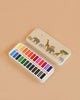 The Konges Sloejd Water Colors Paint Set - Safari comes in a beige tin box with elephant and giraffe art under a night sky. Inside are 18 vibrant rectangular pans, perfect for use with your favorite wooden paint brush.