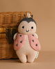 A Maileg Easter Basket Set featuring a knitted plush toy with a smiling face and antennae in a pink ladybug vest with black spots sits in front of a wicker basket on a beige background.